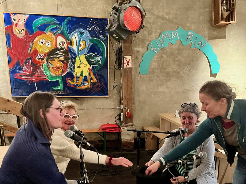 Im Foyer des Theater Metronom sitzen und stehen Schroeder, Hörr, Orth und Roberts im Kreis. Gerade zieht Orth einen Zettel aus einem Hut.